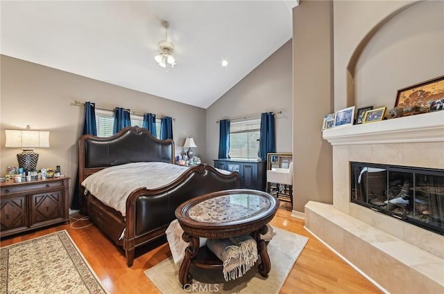 bedroom featuring high vaulted ceiling, a fireplace, recessed lighting, and wood finished floors