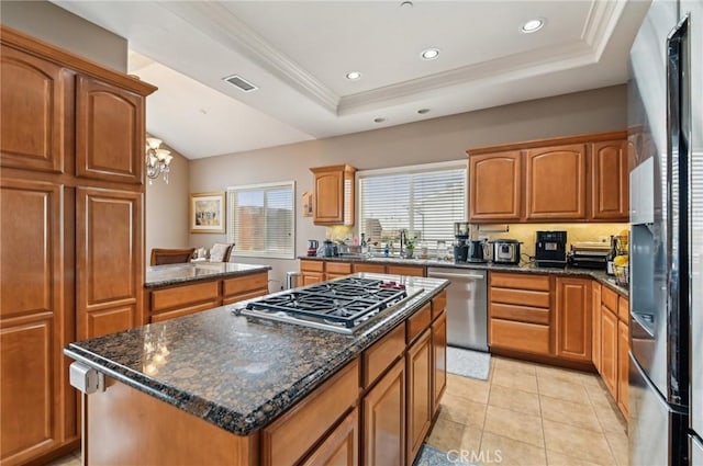 kitchen featuring a center island, a tray ceiling, a healthy amount of sunlight, and stainless steel appliances