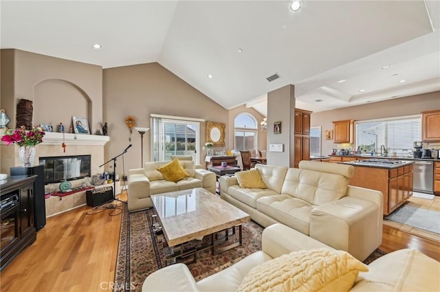 living room featuring visible vents, recessed lighting, a multi sided fireplace, light wood-style flooring, and vaulted ceiling