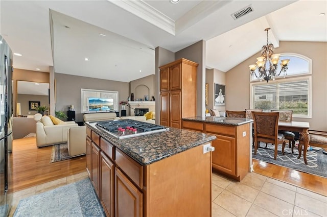 kitchen featuring light tile patterned flooring, a notable chandelier, a center island, stainless steel gas stovetop, and visible vents