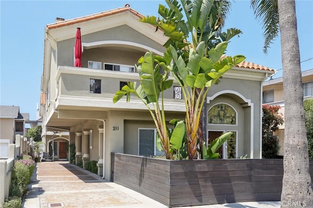 view of front of home with fence, a balcony, and stucco siding