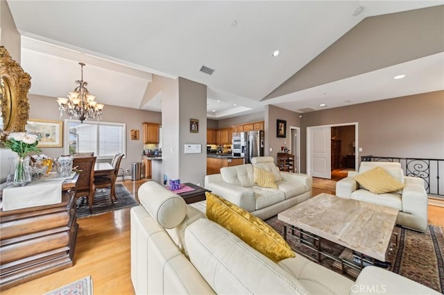 living area with recessed lighting, a notable chandelier, lofted ceiling, and light wood-type flooring