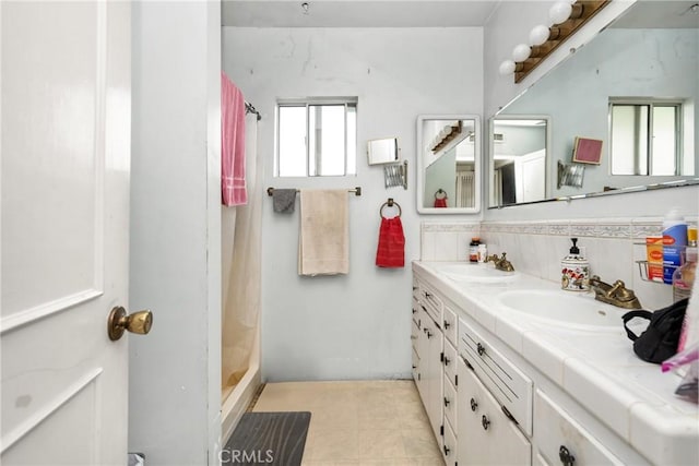 full bath featuring a sink, a stall shower, and double vanity
