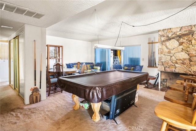 rec room featuring visible vents, carpet floors, a stone fireplace, a textured ceiling, and pool table