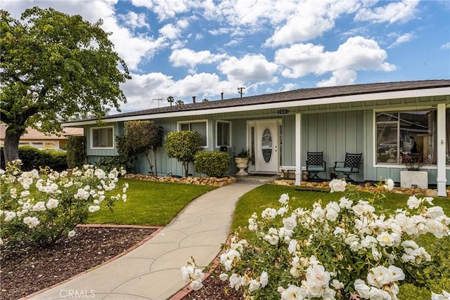ranch-style home with a porch, a front lawn, and board and batten siding