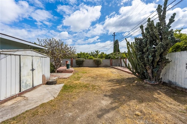 view of yard featuring an outbuilding, a fenced backyard, and a storage unit