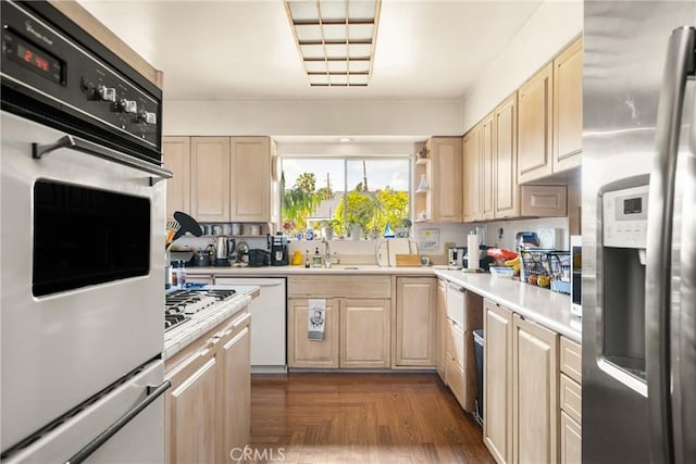 kitchen with white appliances, light countertops, a sink, and light brown cabinets