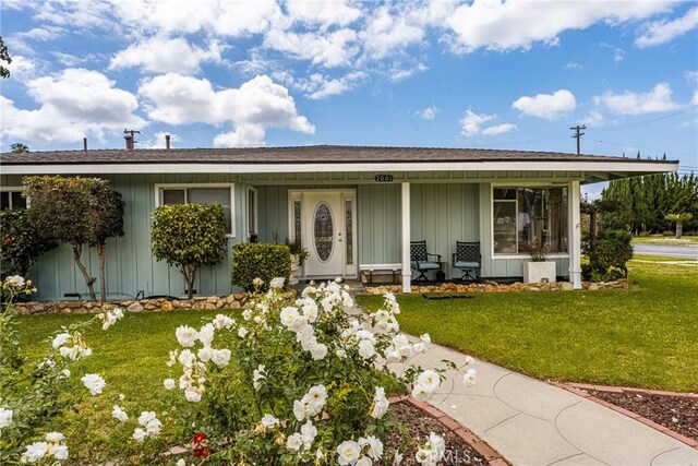 ranch-style house with a shingled roof, board and batten siding, and a front yard
