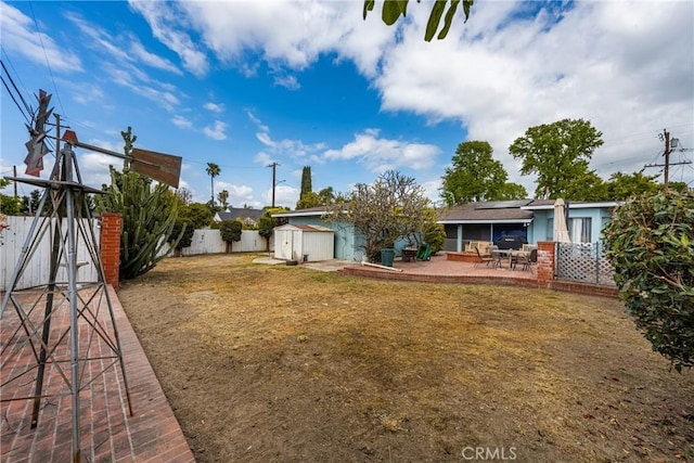 view of yard featuring an outbuilding, a fenced backyard, a patio area, and a storage unit