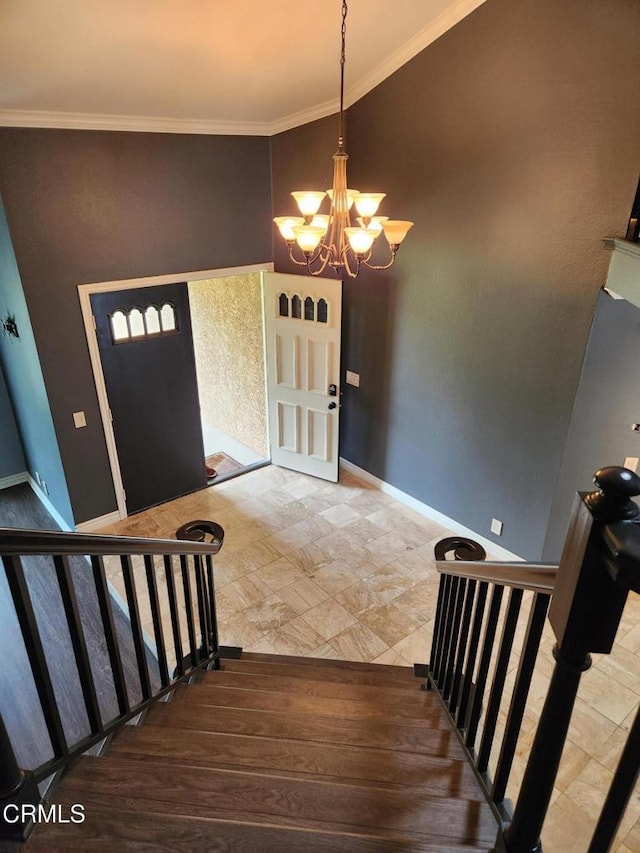 foyer featuring an inviting chandelier, ornamental molding, and baseboards