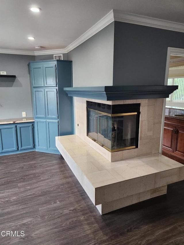 unfurnished living room with a tiled fireplace, recessed lighting, crown molding, and dark wood-style floors