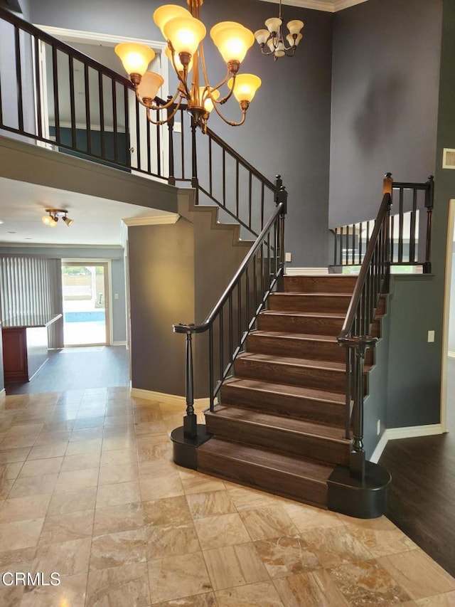 stairway with baseboards, a towering ceiling, and a chandelier