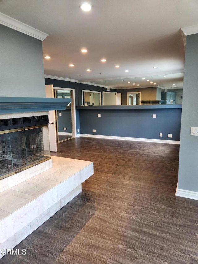 unfurnished living room with crown molding, wood finished floors, baseboards, recessed lighting, and a tiled fireplace