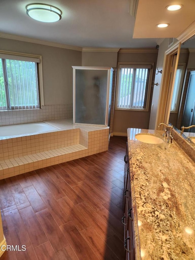 full bath with ornamental molding, a shower stall, a garden tub, and wood finished floors