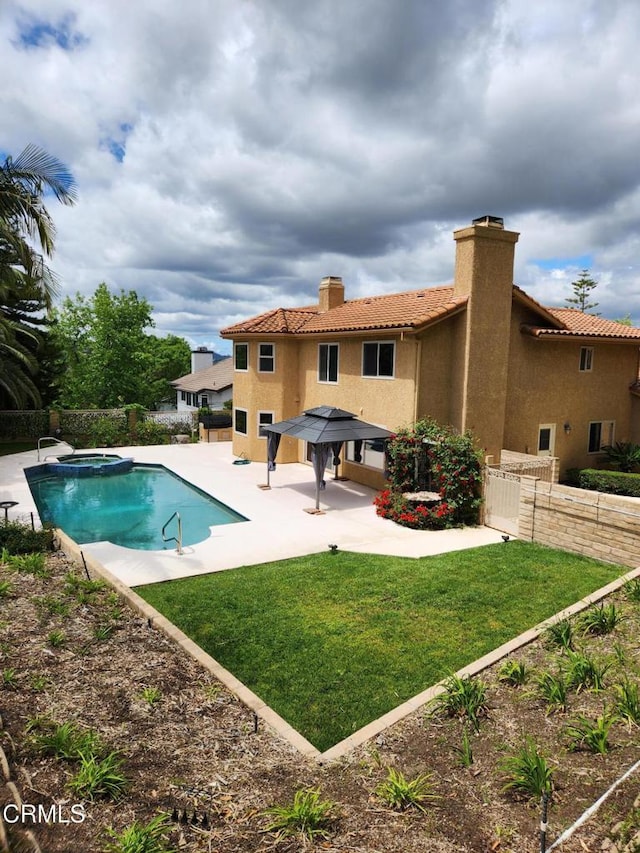 view of swimming pool featuring a yard, a pool with connected hot tub, fence, and a patio area