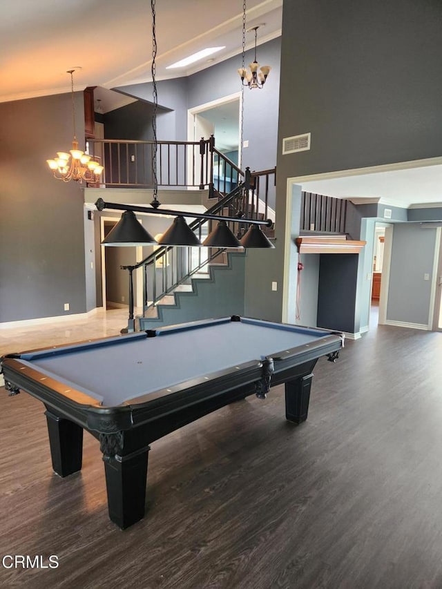 playroom featuring a towering ceiling, wood finished floors, a chandelier, and visible vents