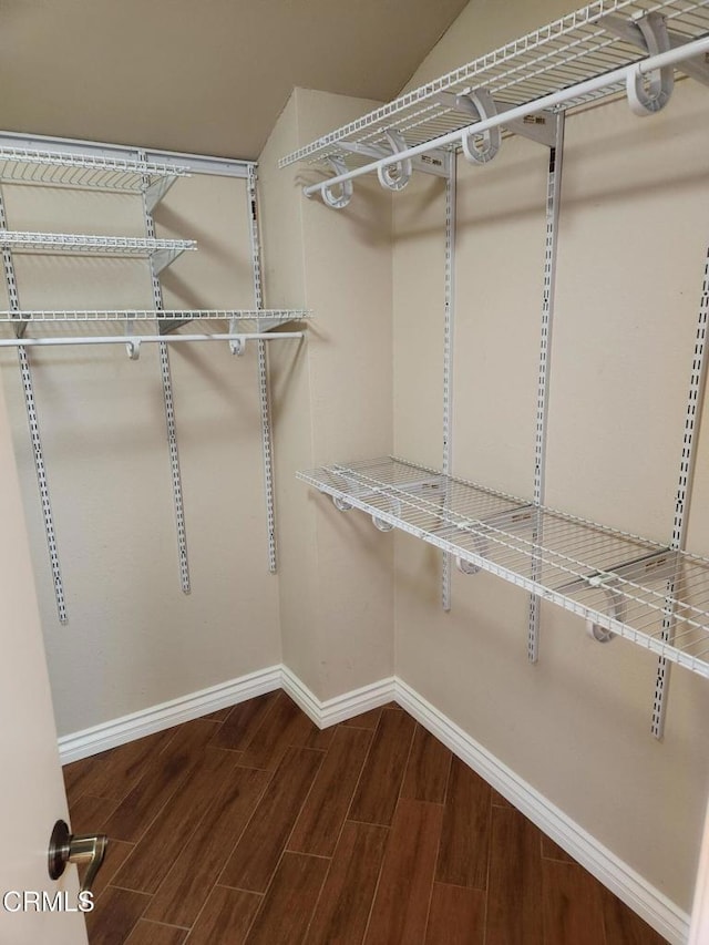 spacious closet with dark wood finished floors and lofted ceiling