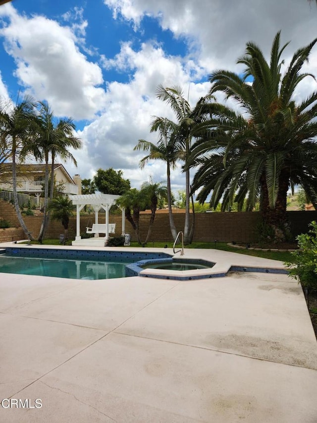 view of pool with a pergola, a pool with connected hot tub, fence, and a patio area
