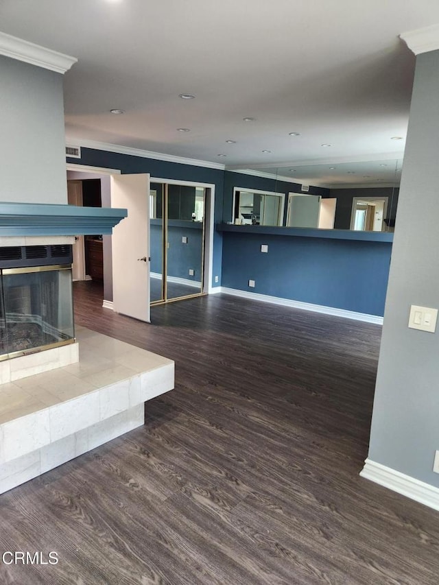 unfurnished living room with crown molding, baseboards, wood finished floors, and a tile fireplace