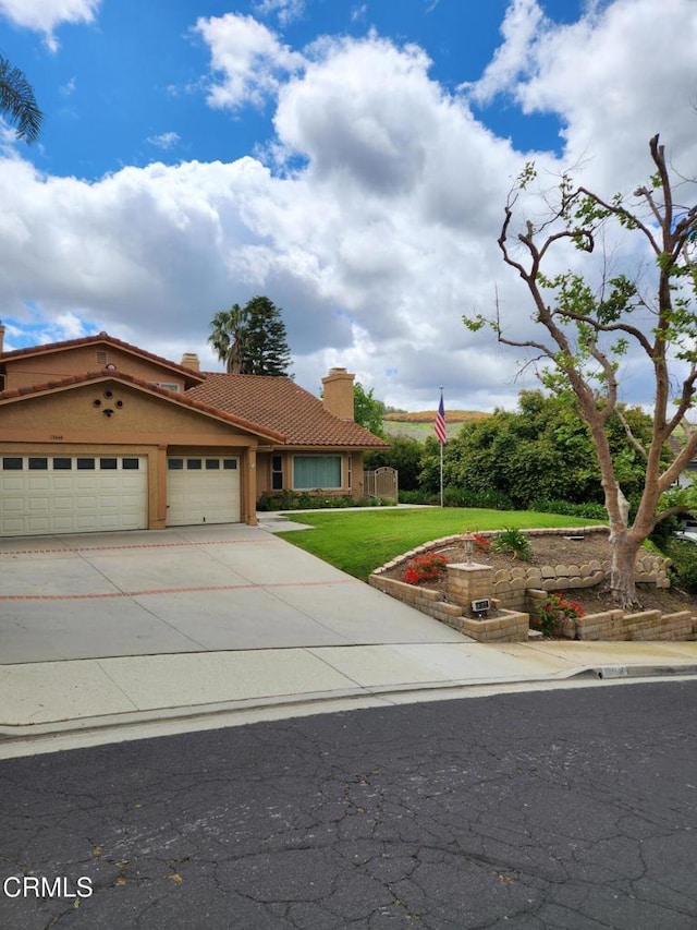 mediterranean / spanish home featuring a garage, a front yard, a chimney, concrete driveway, and a tiled roof