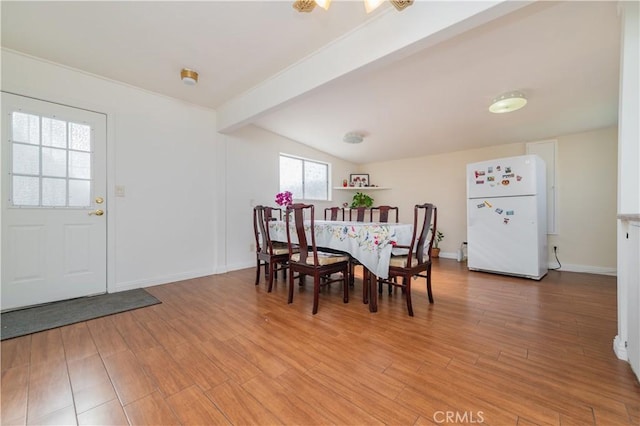 dining room featuring light wood-style floors, baseboards, and lofted ceiling with beams
