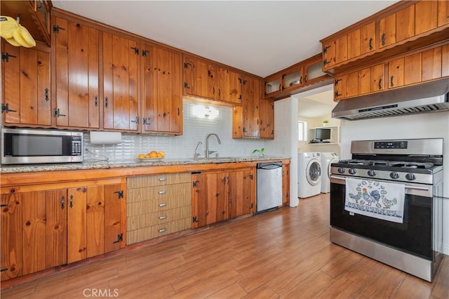 kitchen with separate washer and dryer, decorative backsplash, appliances with stainless steel finishes, and under cabinet range hood