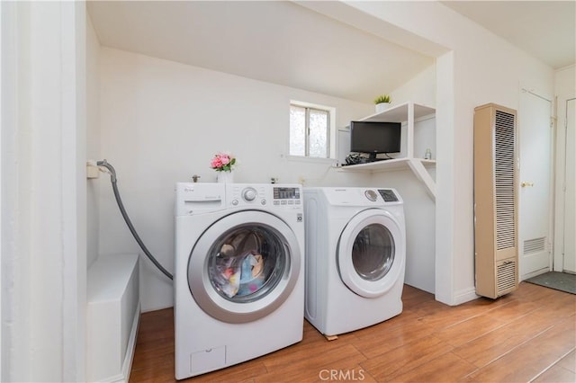 laundry area featuring light wood-style floors, separate washer and dryer, laundry area, and a heating unit