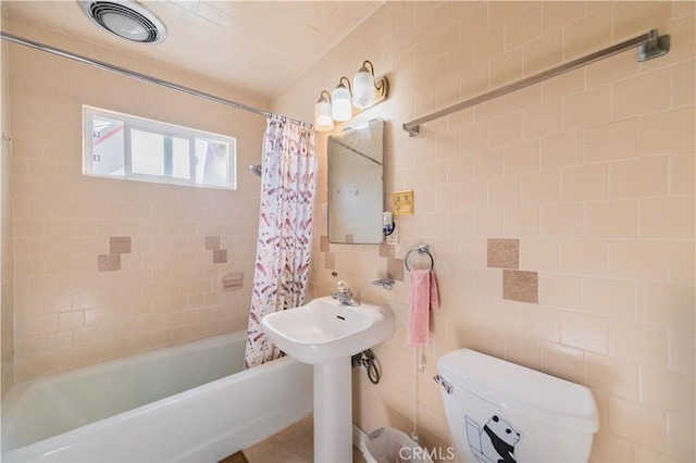 full bathroom featuring tile walls, toilet, shower / bathtub combination with curtain, and visible vents
