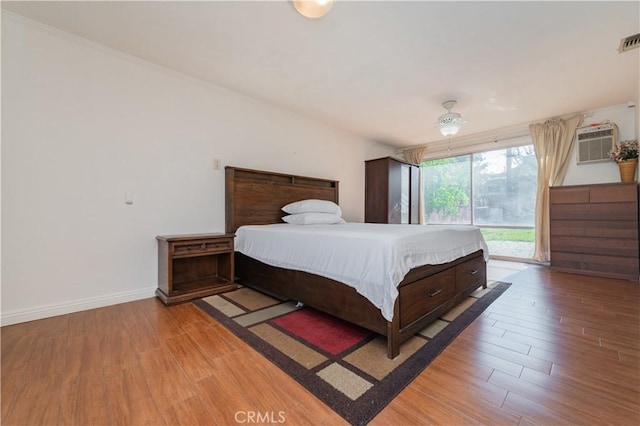 bedroom featuring light wood-type flooring, baseboards, a wall mounted AC, and visible vents