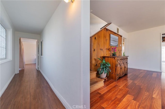 corridor with baseboards, visible vents, dark wood-style floors, and a healthy amount of sunlight