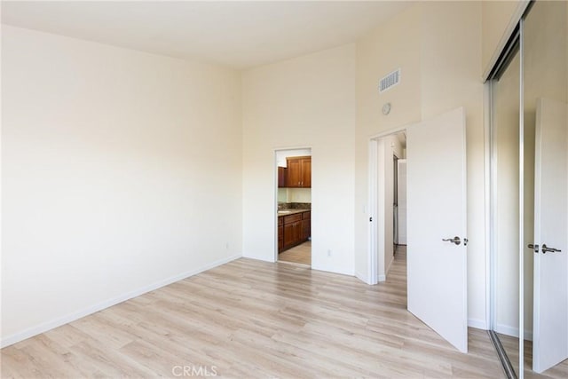 30902 Clubhouse Dr Unit 24E, Laguna Niguel, CA 92677 - unfurnished bedroom featuring light wood-style floors, baseboards, a closet, a high ceiling, and connected bathroom