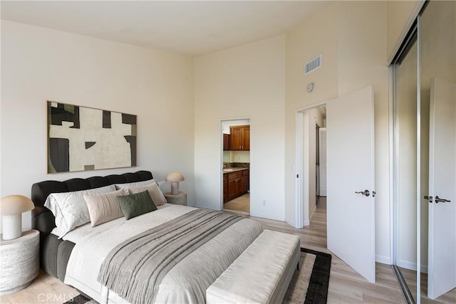 30902 Clubhouse Dr Unit 24E, Laguna Niguel, CA 92677 - bedroom with light wood-style flooring, a high ceiling, and connected bathroom