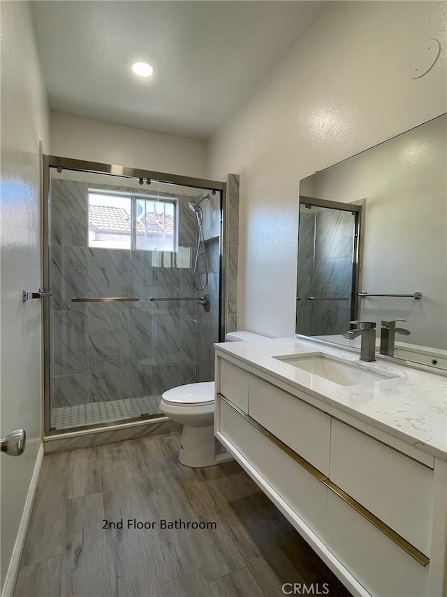 full bath featuring vanity, a stall shower, toilet, and wood finished floors