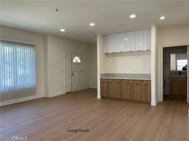 kitchen featuring light wood-type flooring, light countertops, white cabinetry, and a wealth of natural light