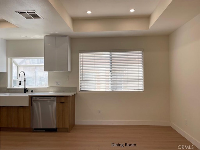 kitchen with light wood-style floors, baseboards, stainless steel dishwasher, visible vents, and modern cabinets