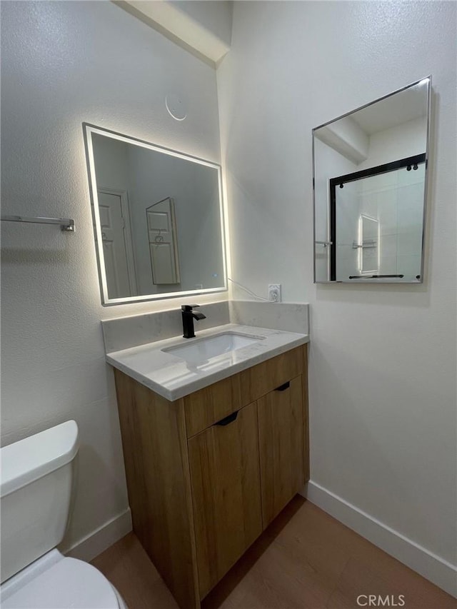 full bathroom with toilet, baseboards, a shower with shower door, and vanity