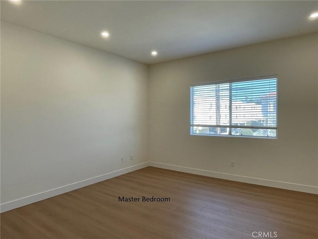 empty room featuring baseboards, recessed lighting, and wood finished floors