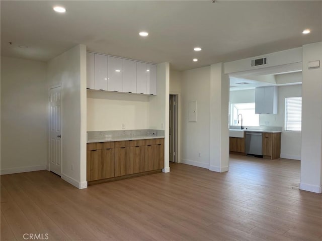 kitchen with visible vents, dishwasher, light countertops, baseboards, and light wood-style floors