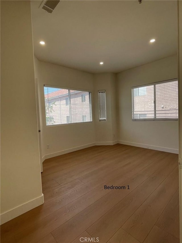 unfurnished room featuring visible vents, recessed lighting, baseboards, and wood-type flooring