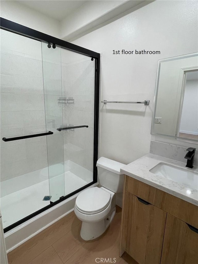 bathroom featuring toilet, a shower stall, and vanity