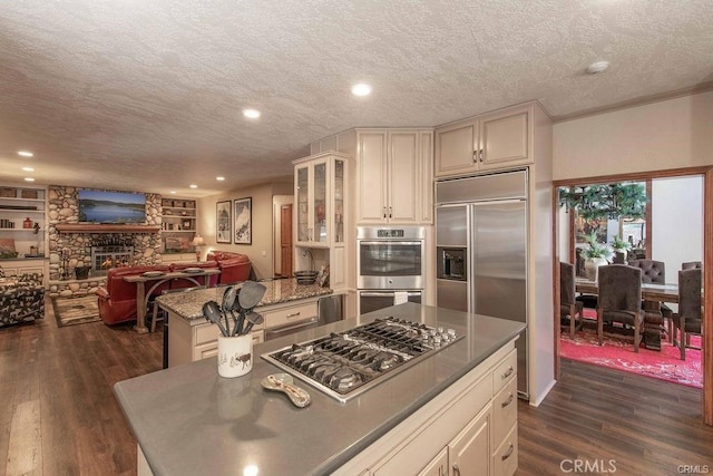 kitchen with a kitchen island, stainless steel appliances, dark wood-style flooring, and a textured ceiling