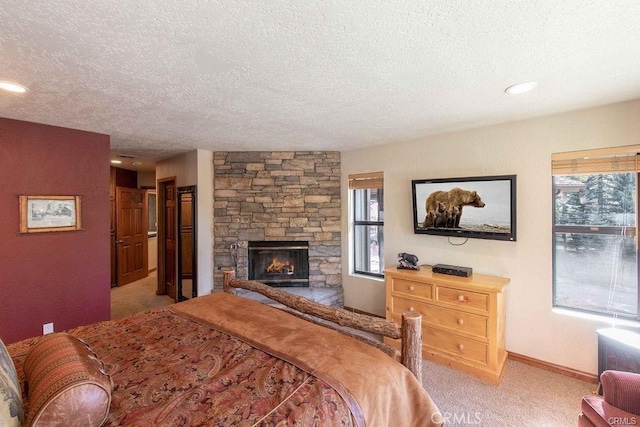 bedroom with a textured ceiling, light colored carpet, baseboards, and a fireplace