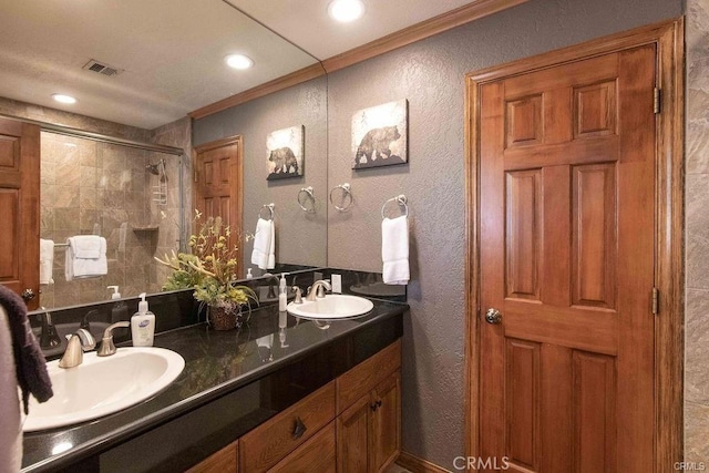 full bath with a textured wall, a sink, visible vents, ornamental molding, and a stall shower