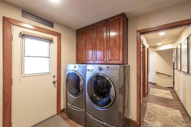 laundry area featuring washing machine and clothes dryer, recessed lighting, light wood-style flooring, and cabinet space