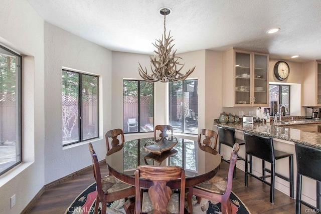 dining room with dark wood-style flooring, a textured wall, a textured ceiling, a chandelier, and baseboards