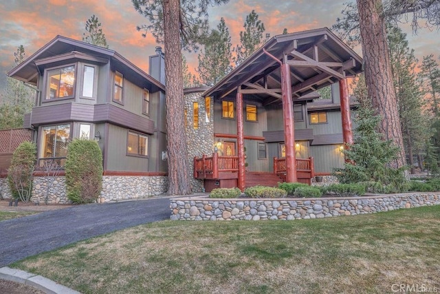 view of front of property with a chimney, a front lawn, and stone siding