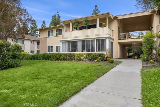 40N Calle Aragon, Laguna Woods, CA 92637 - back of property with stucco siding, a balcony, a carport, a yard, and driveway