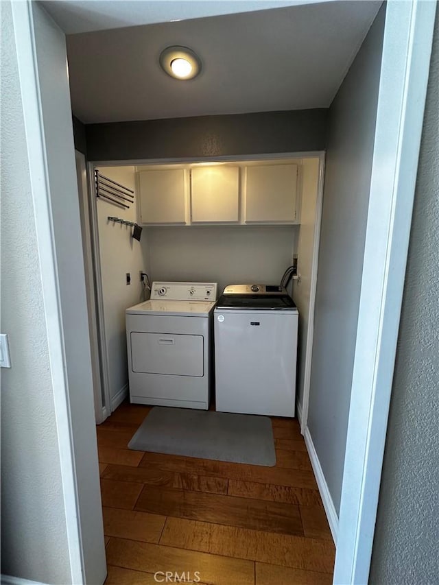 laundry area featuring cabinet space, separate washer and dryer, baseboards, and hardwood / wood-style floors