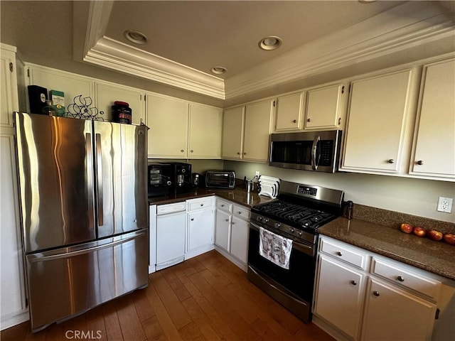 kitchen with appliances with stainless steel finishes, dark wood-type flooring, white cabinetry, and a raised ceiling