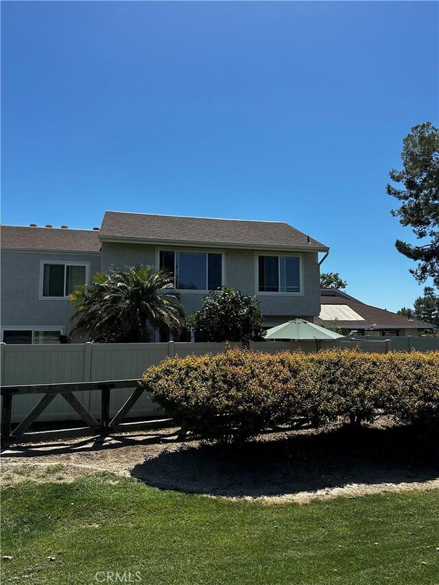 ranch-style house with fence, a front lawn, and stucco siding